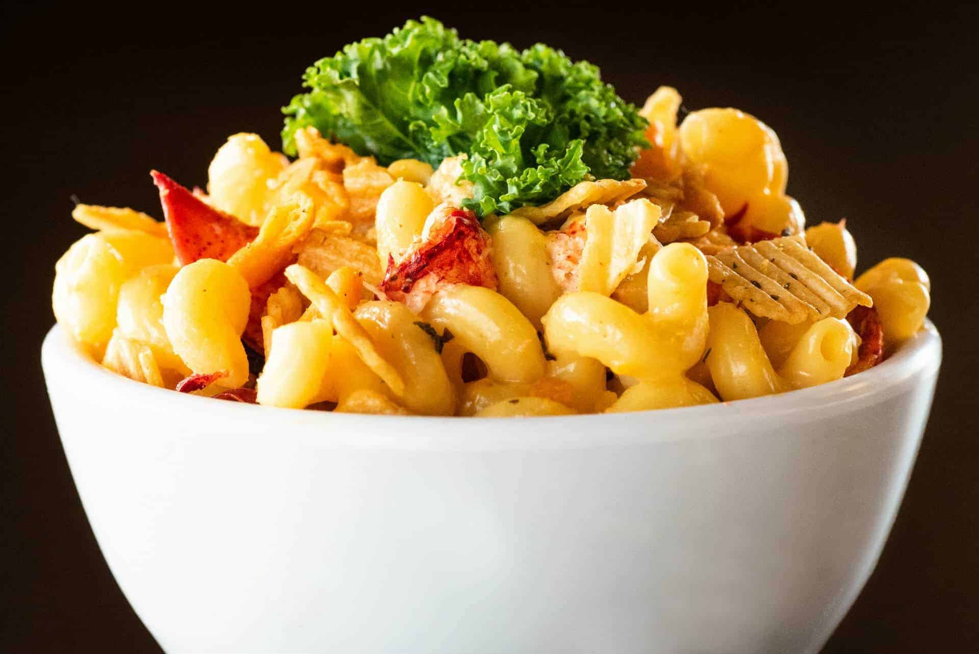 Fresh Island Shrimp Pasta with Vegetables and Lettuce Delicious shrimp pasta with vegetables and lettuce garnish in a white bowl.